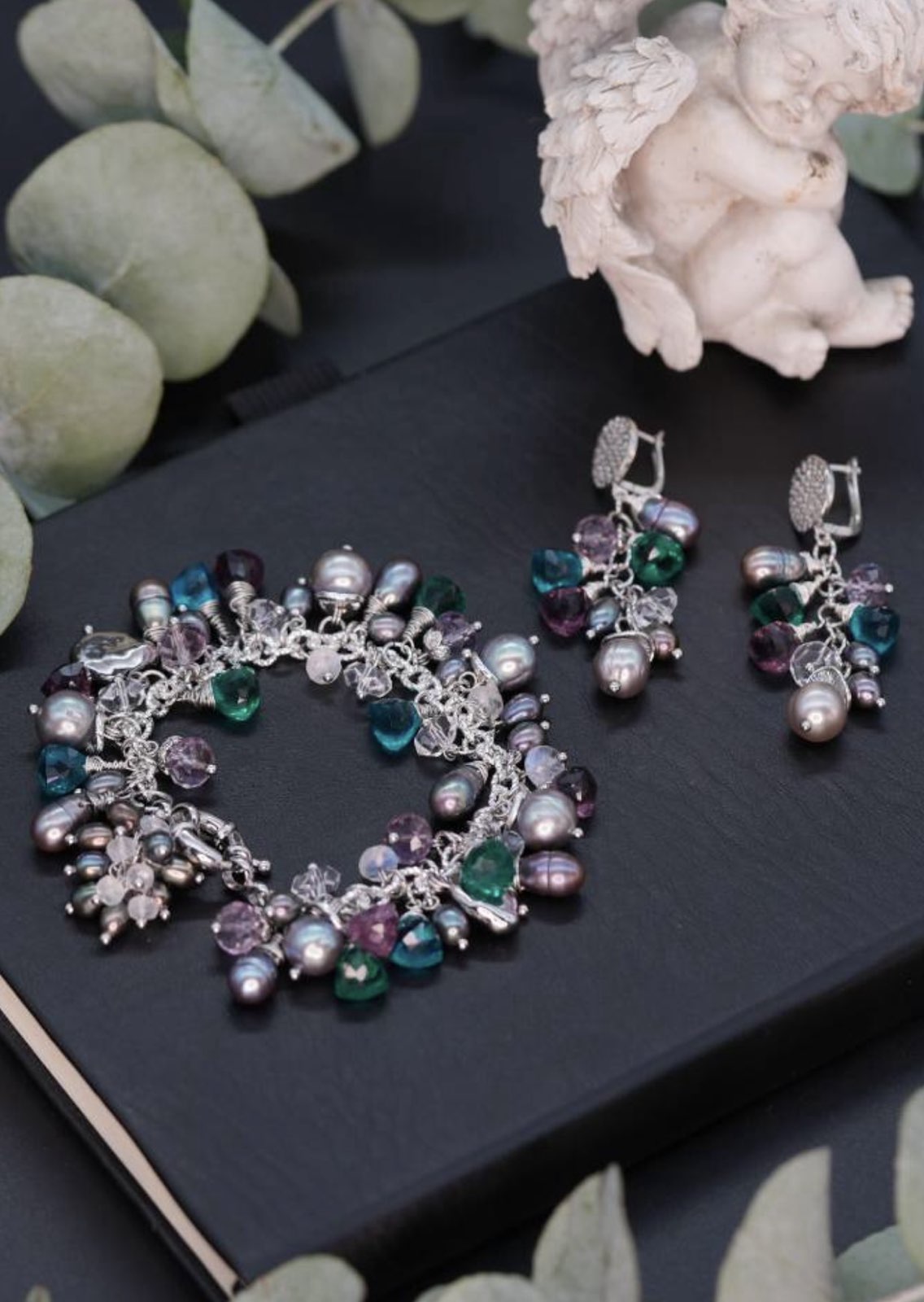 Midnight Garden bracelet and earrings arranged on a dark book