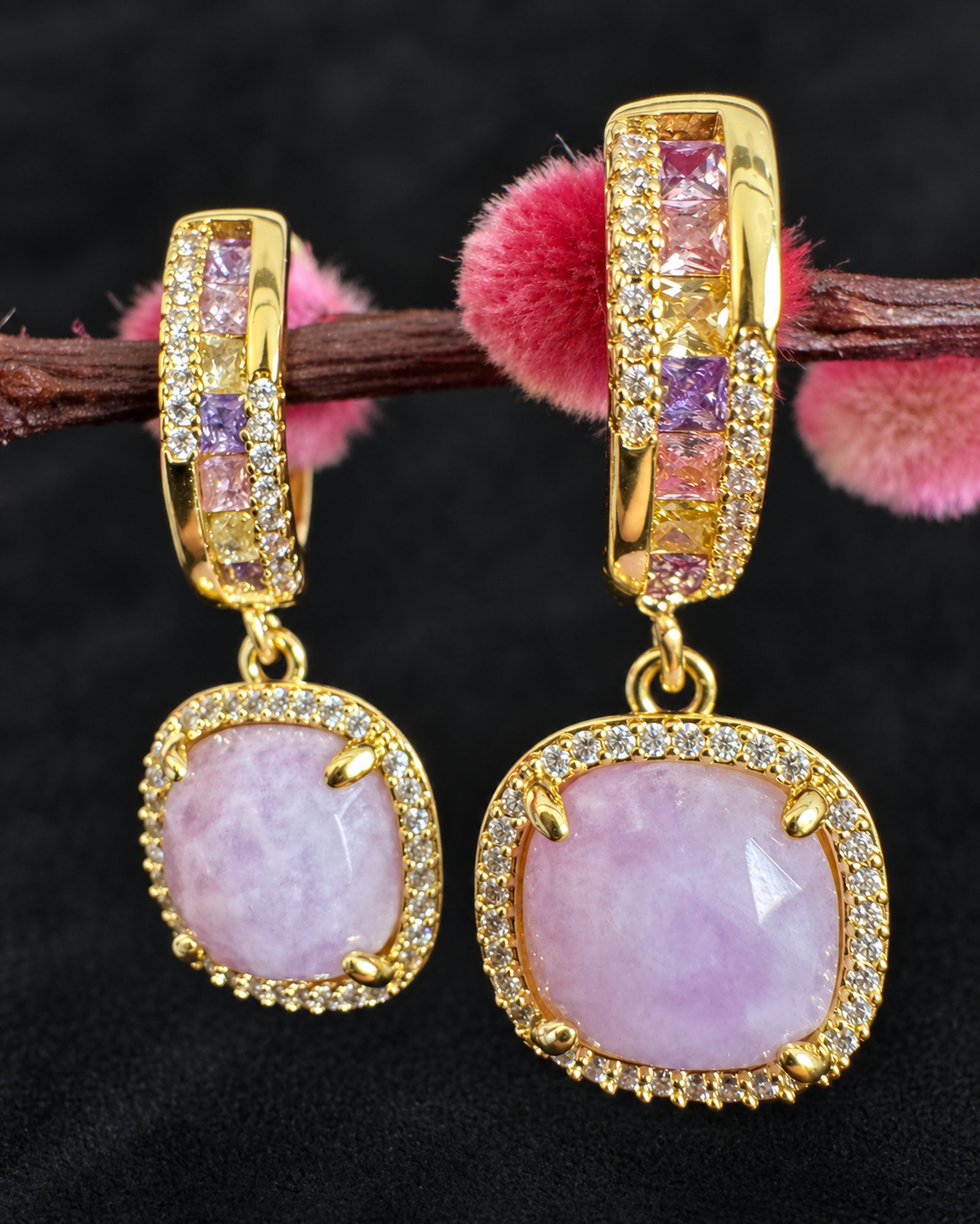 Close-up of pale lavender cushion-shaped drops with clear-looking borders and decorated gold-toned hoops.
