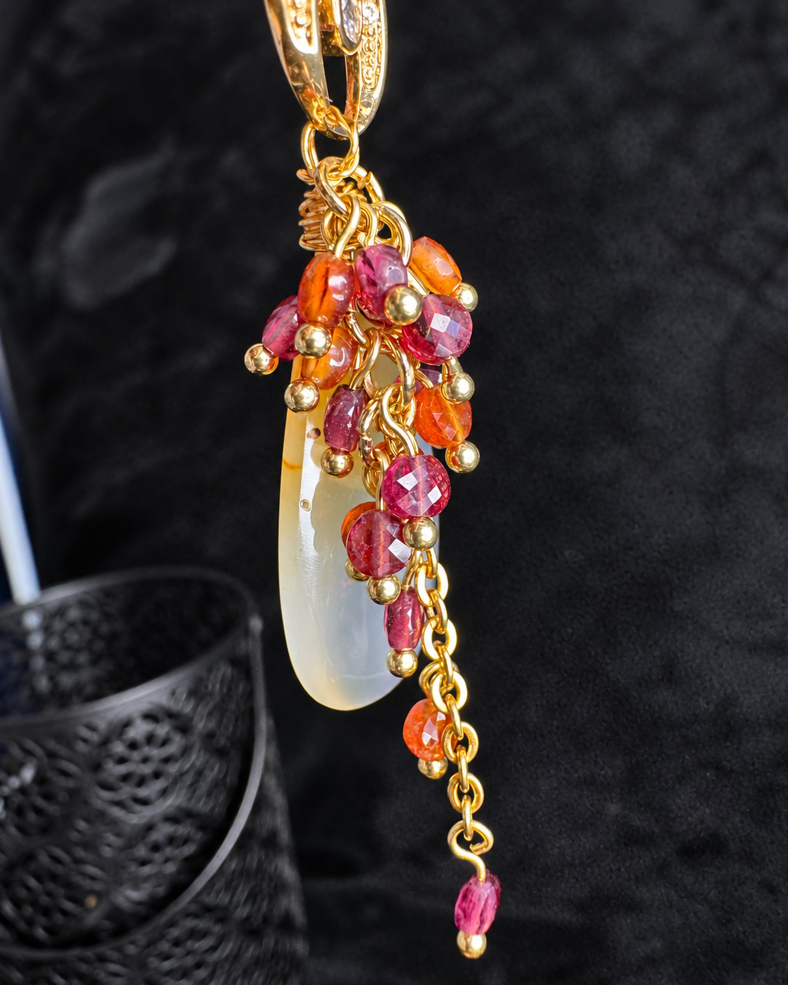 Side detail of one earring showing pink and orange bead clusters, a pale drop and a gold-toned chain ending in a pink bead.