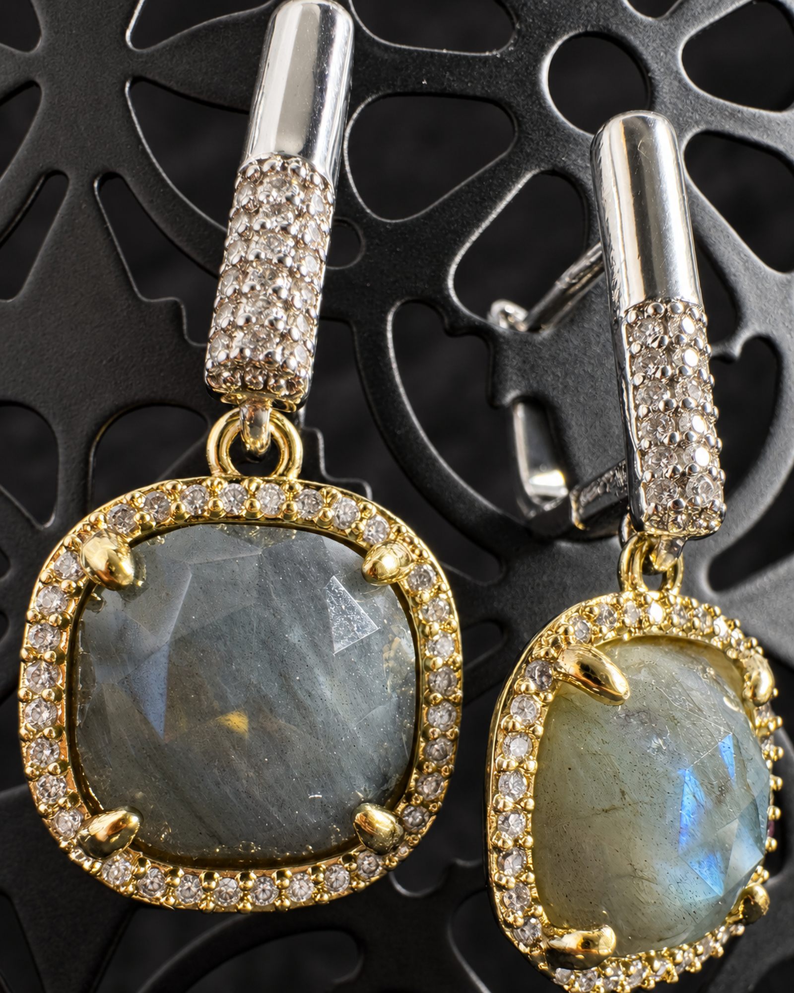 Close-up of the grey drops, gold-toned surrounds, prongs and textured silver-toned fastenings, with parts of the earrings cropped by the frame.